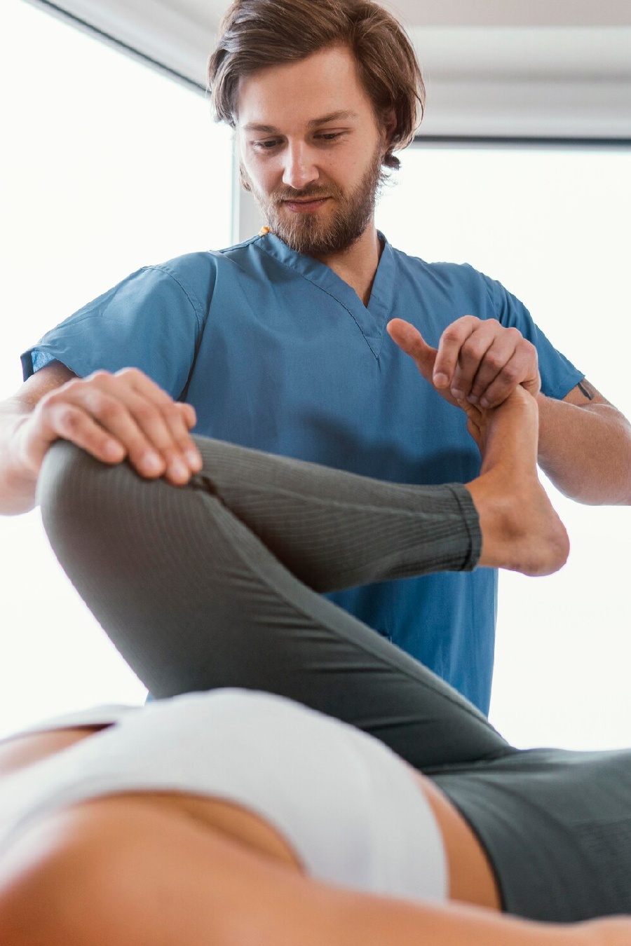 fisio-doblando la rodilla de la paciente fisio doblando la rodilla de la paciente